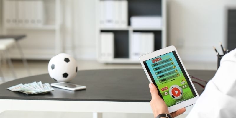 Một người chơi đang lướt xem các tỷ lệ kèo trên thiết bị di động, biểu cảm tập trung